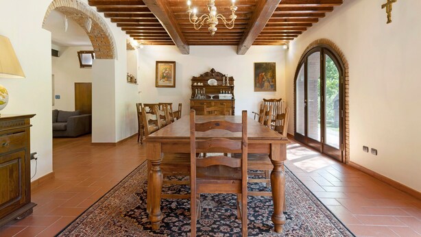 Un coin repas avec une table en bois, des chaises, un lustre et un tapis à motifs.