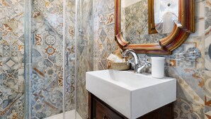 Une salle de bain avec une douche, un lavabo, un miroir et des carreaux décorés.