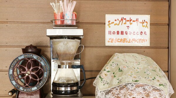 Un moulin à café, une table recouverte d’une nappe en dentelle et une enseigne avec du texte en japonais.