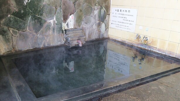 Eine Steinsäule mit Fliesenboden und einem Schild in japanischer Schrift.