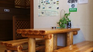 Eine Holzbänke und ein Tisch in einem Raum mit einer Karte und einem Schild für einen Raucherbereich an der Wand.