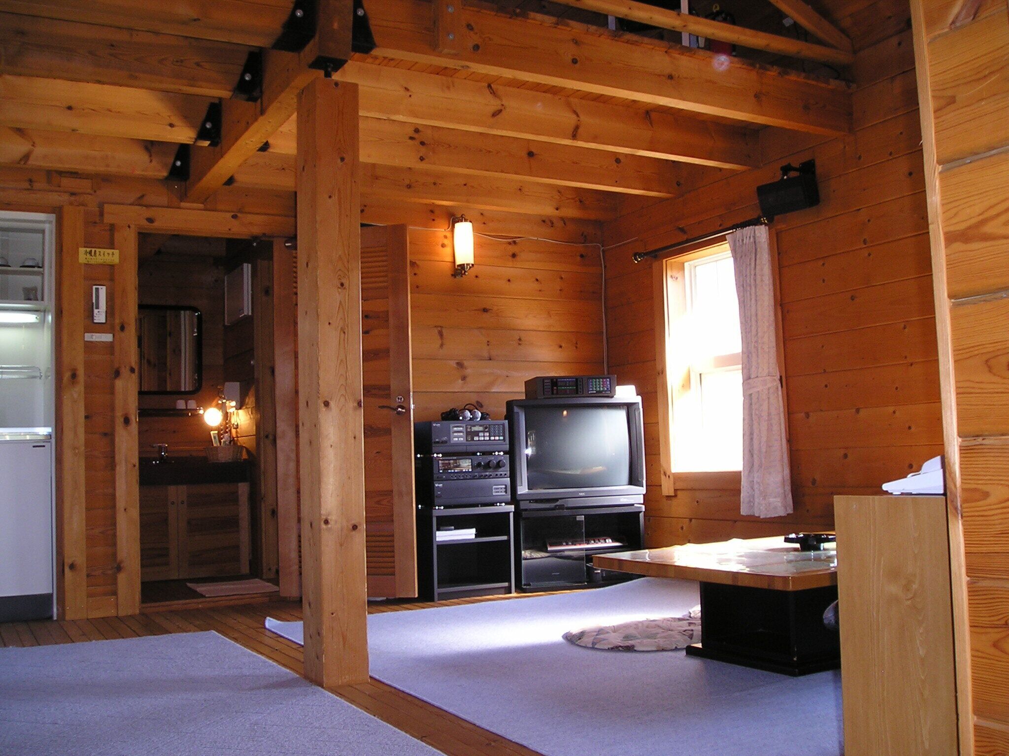 Een houten blokhut vanbinnen met een kitchenette, een televisie en een raam.