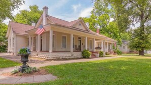 A two-story house with a porch, a flag, and a well-maintained lawn.