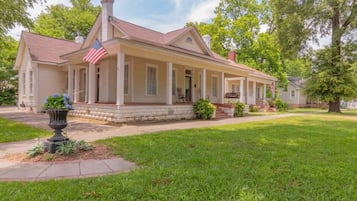 A two-story house with a porch, a flag, and a well-maintained lawn.