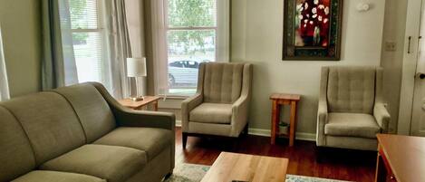 A living room with a sofa, two armchairs, a coffee table, and a small side table.