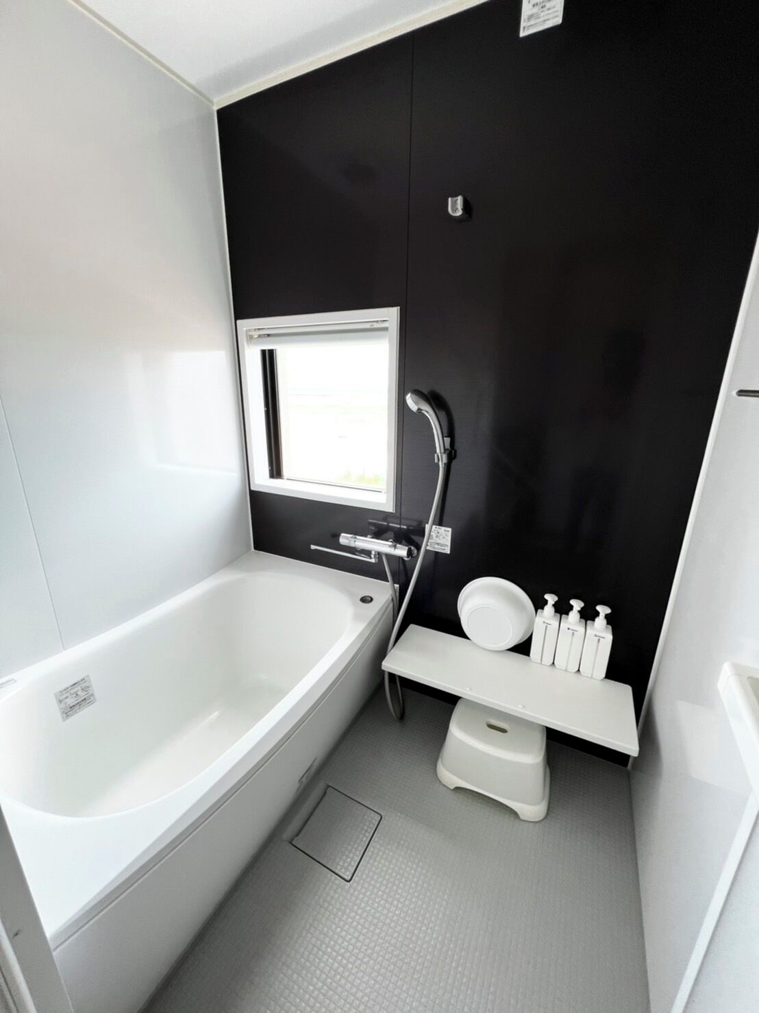 A modern bathroom with a bathtub, a toilet, a shower, and a window.