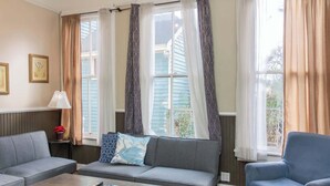 A living room with a grey sofa, a blue armchair, a wooden coffee table, and a lamp. - Large Downtown Home - The Sunny Southern Manse (Columbus)