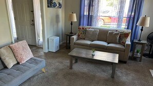 Un salon comprenant un canapé, une table basse, une table d’appoint, une lampe et un ventilateur.