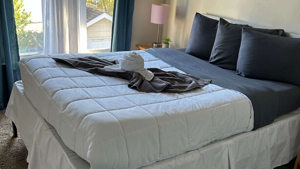 Une chambre à coucher avec un lit, une lampe de chevet et une fenêtre avec des rideaux.