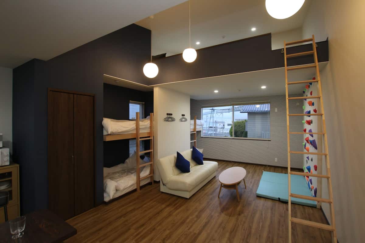 A modern room with bunk beds, a sofa, a small table, and a ladder.