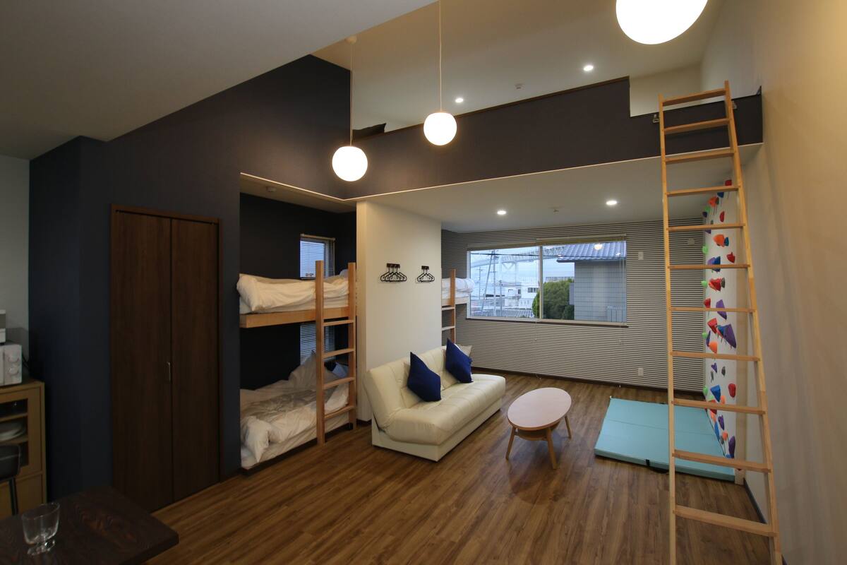 Une chambre moderne avec des lits superposés, un canapé, une petite table et une échelle.
