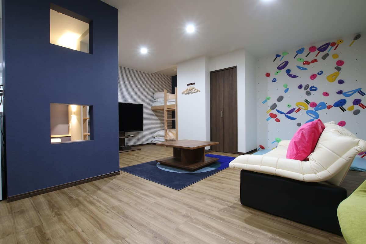 A modern living room with a sofa, a TV, a wooden table, and a wall with colorful wall art.