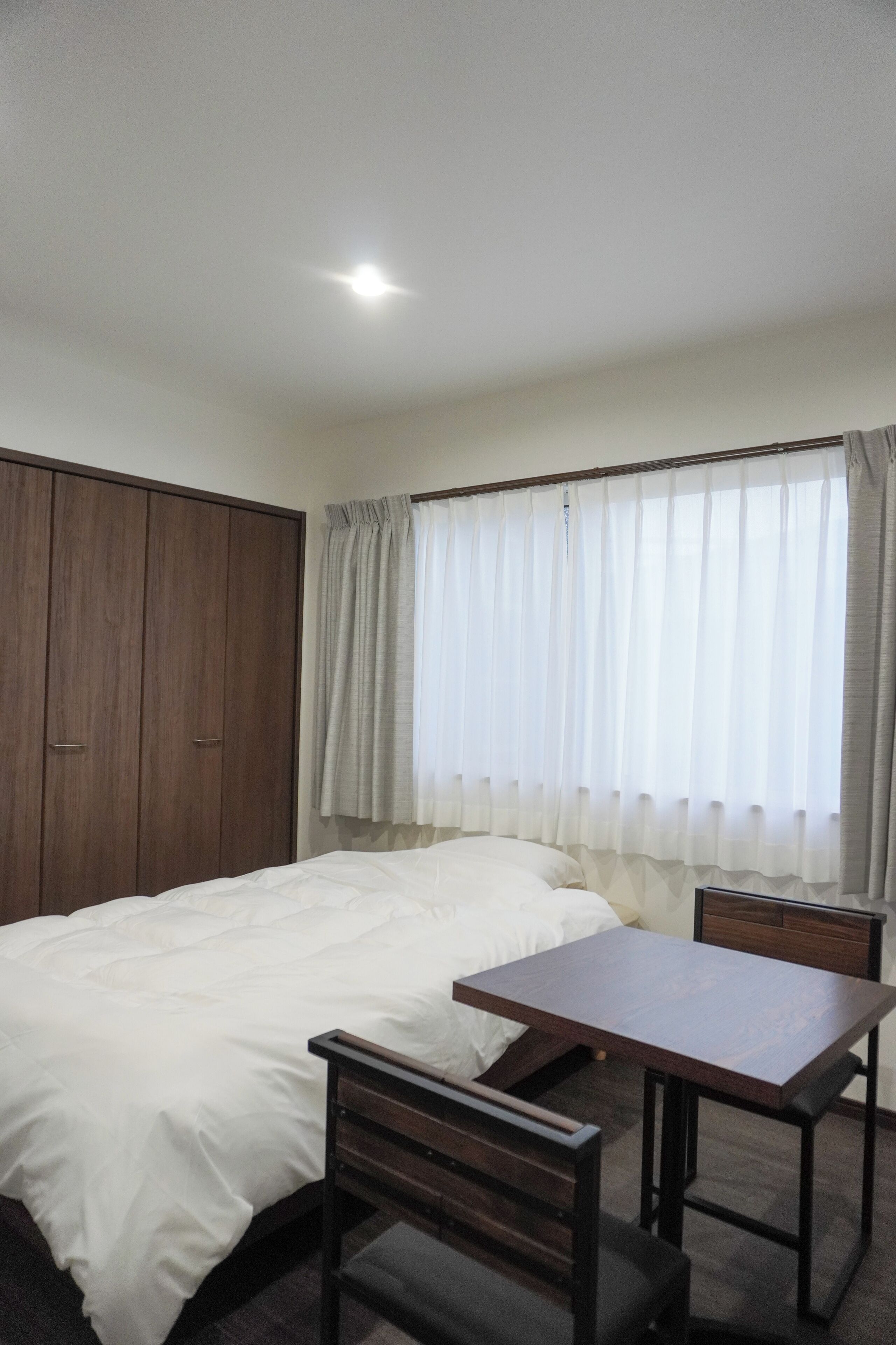 Une chambre à coucher avec un lit, une armoire en bois, une table et une chaise.