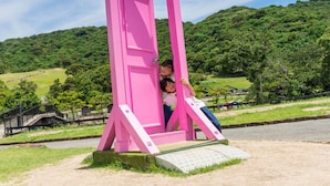 Una estructura rosa que parece una puerta en un entorno exterior, con un paisaje montañoso al fondo.