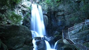 Una cascada con una escalera de metal que sube a una plataforma de observación.