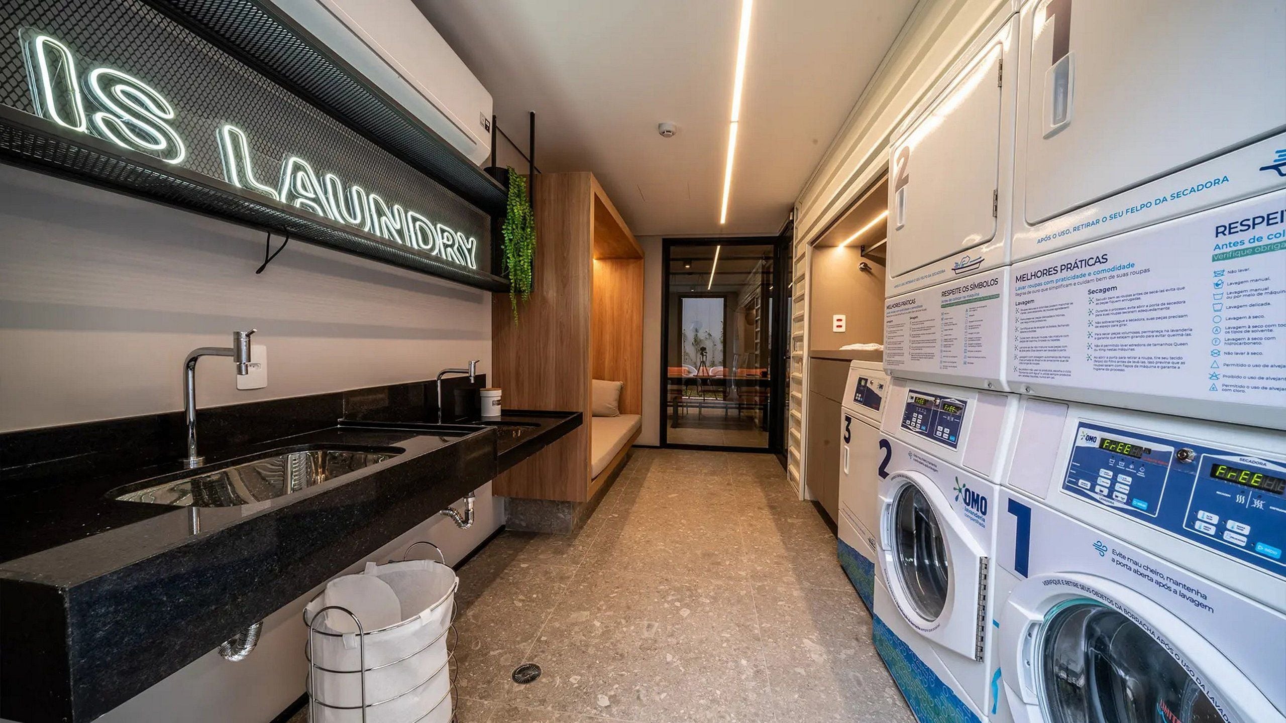 A modern laundry facility with a neon sign, a sink, and multiple washing machines.