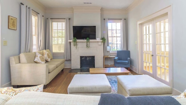 A living room with a fireplace, a sofa, a blue armchair, and a television. - Midtown Main House w/ BBQ, Pets OK, Near Downtown (Columbus)