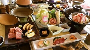 Diverse etenswaren en kookgerei op een tafel, waaronder pannen, kommen en borden met verschillende soorten eten.