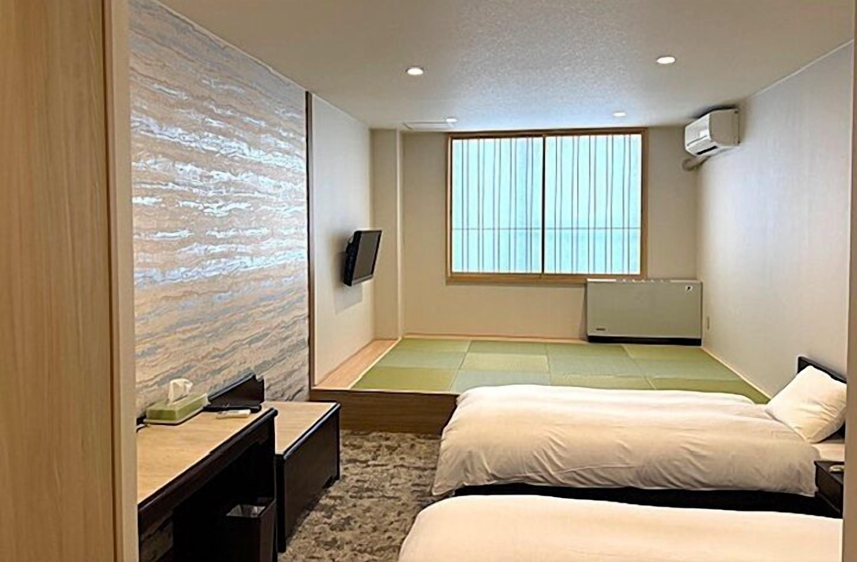A hotel room with a bed, a desk, a television, and a large window.