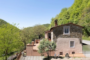 A stone building with a balcony, surrounded by trees and a clear sky.