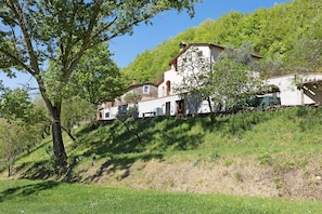 A hillside property with multiple buildings, including a large house with a balcony and a smaller structure.