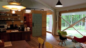 A wooden interior with a kitchen, dining area, and large windows. - Morinonakano Kissatooyado Morikurasu (Maniwa)