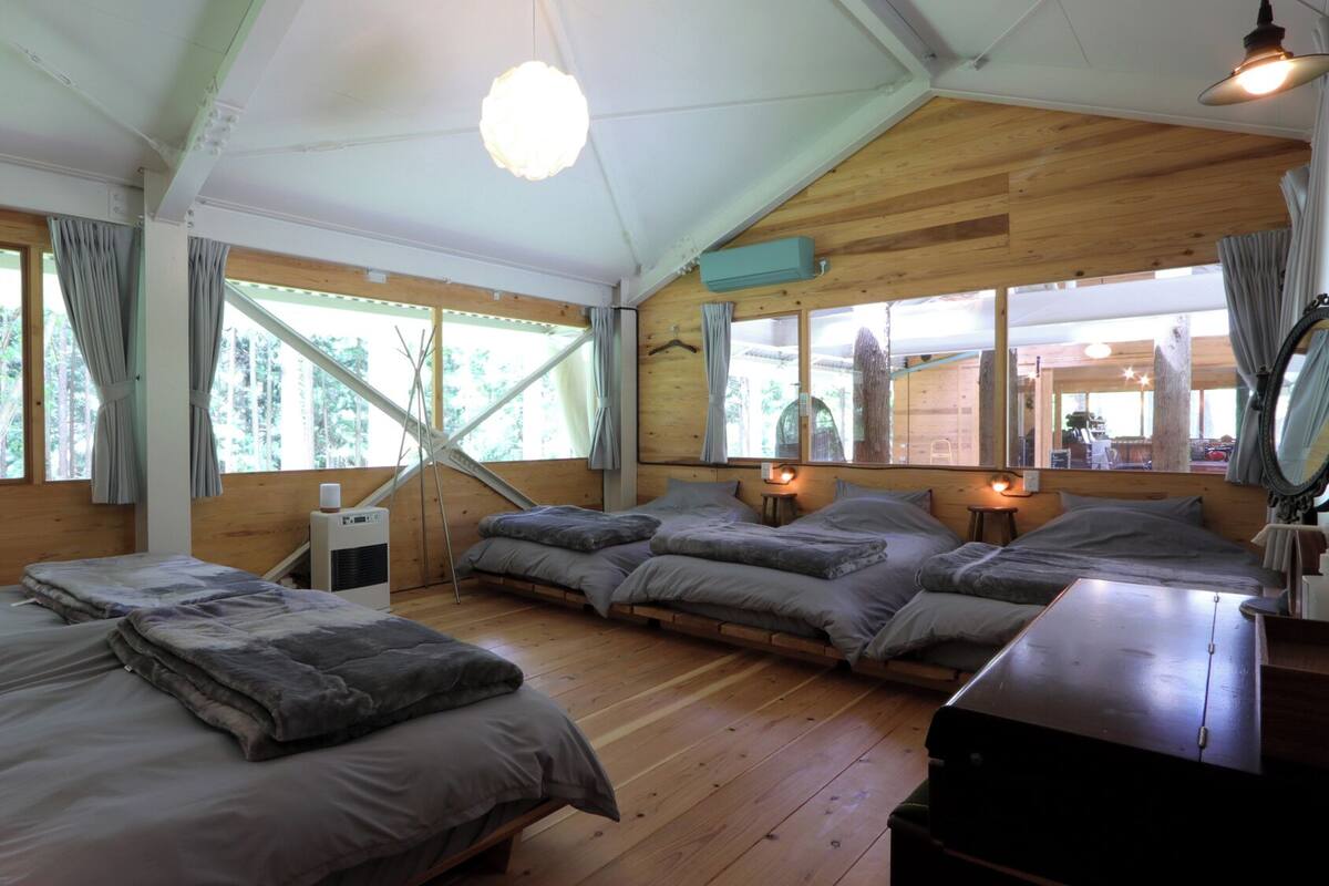 A cabin with a loft bed, a desk, and a large window.