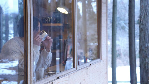 A person inside a room with a window, holding a cup. - Morinonakano Kissatooyado Morikurasu (Maniwa)