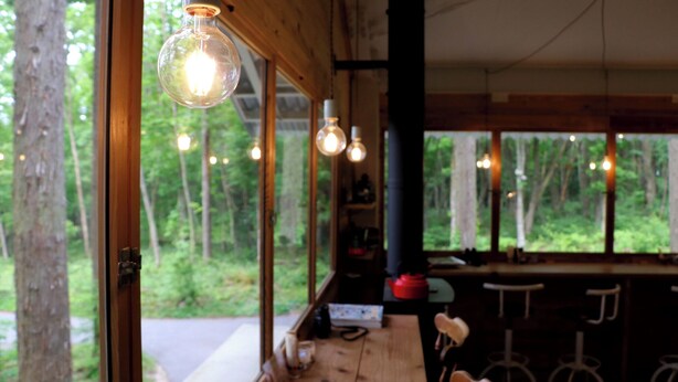 A wooden interior with large windows, a bar area, and hanging light fixtures. - Morinonakano Kissatooyado Morikurasu (Maniwa)