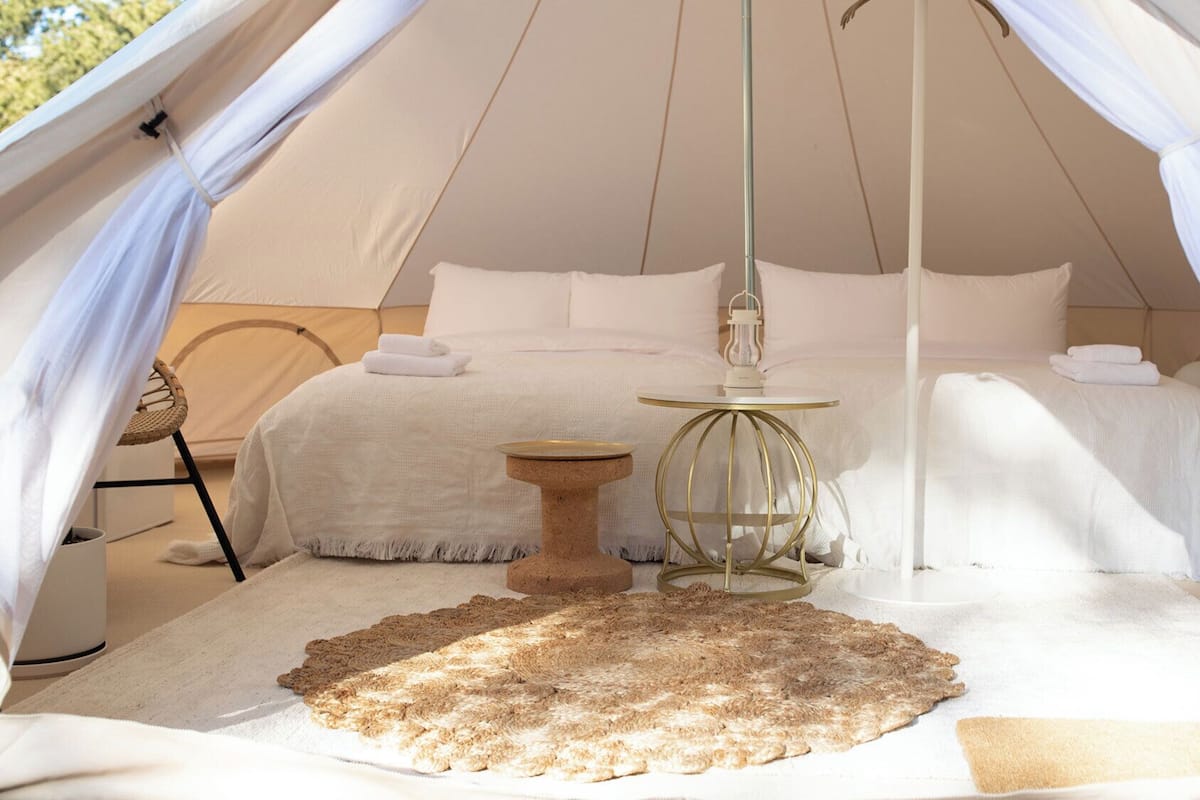 Ein Zelt mit Bett, einem kleinen runden Tisch und einem Teppich.