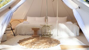 A tent with a bed, a small round table, and a rug. - Small Planet Camp & Grill (Chiba)