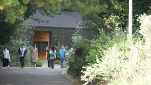 A building with a reception area, surrounded by dense greenery. - Small Planet Camp & Grill (Chiba)