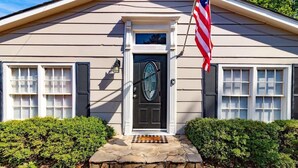 A house with a front door, an American flag, and a stone step leading to the entrance. - Pet-Friendly Condo w/ Free Parking, Near Downtown (Columbus)