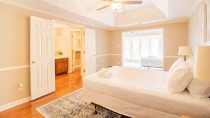A bedroom with a bed, a ceiling fan, a door leading to a bathroom, and a view of a balcony. - Pet-Friendly Condo w/ Free Parking, Near Downtown (Columbus)