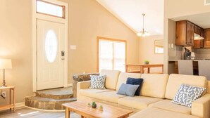 A living room with a sofa, coffee table, and a door with a light fixture. - Pet-Friendly Condo w/ Free Parking, Near Downtown (Columbus)