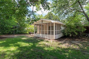 A covered outdoor area with a lattice railing, surrounded by trees and grass. - Family-Friendly Near Fort Benning! Crimson Ranch (Columbus)