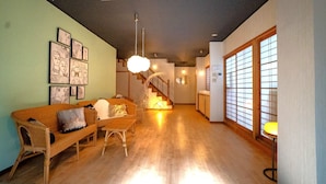 A living room with a sofa, a chair, a staircase, and a large window. - Alloggio Nanki Shirahama (Shirahama)