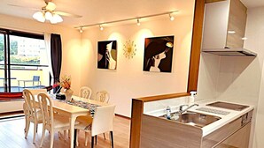 A modern kitchen with a built-in stove, a sink, and a dining area with a table and chairs. - Alloggio Nanki Shirahama (Shirahama)