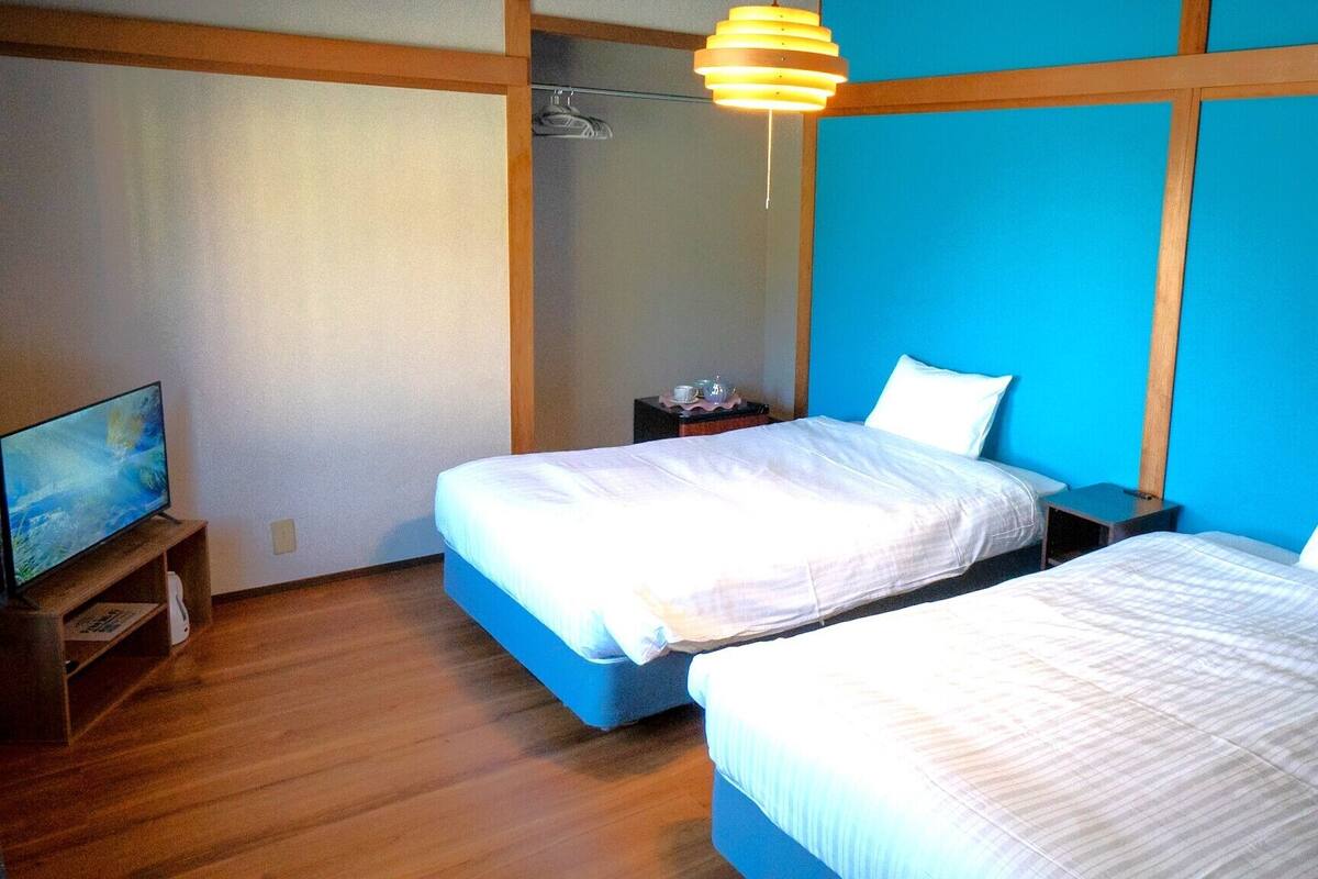 Een hotelkamer met twee bedden, een televisie en een houten vloer.