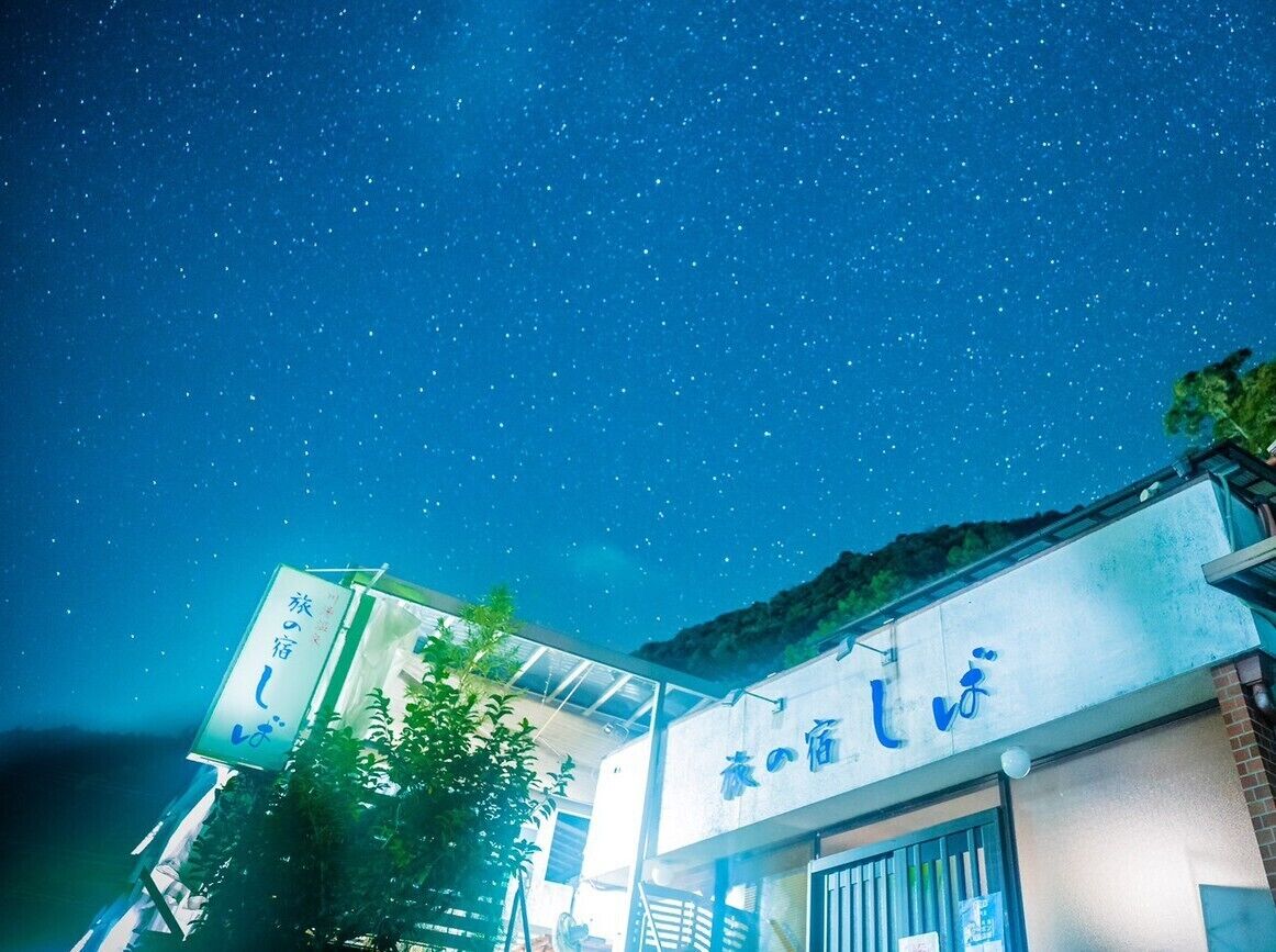 Ein Gebäude mit japanischer Beschilderung, ein klarer Nachthimmel und ein Sternenhimmel.