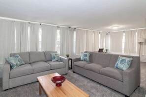 A living room with two grey sofas, a wooden coffee table, and a red bowl. - Pet-Friendly Home, Walk to Riverwalk, Free (Columbus)