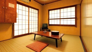 A traditional Japanese room with tatami flooring, a low table, a television, and sliding doors. - Usami Onsen Fugu Jizakana Ryori no Yado Otsuka (Ito)
