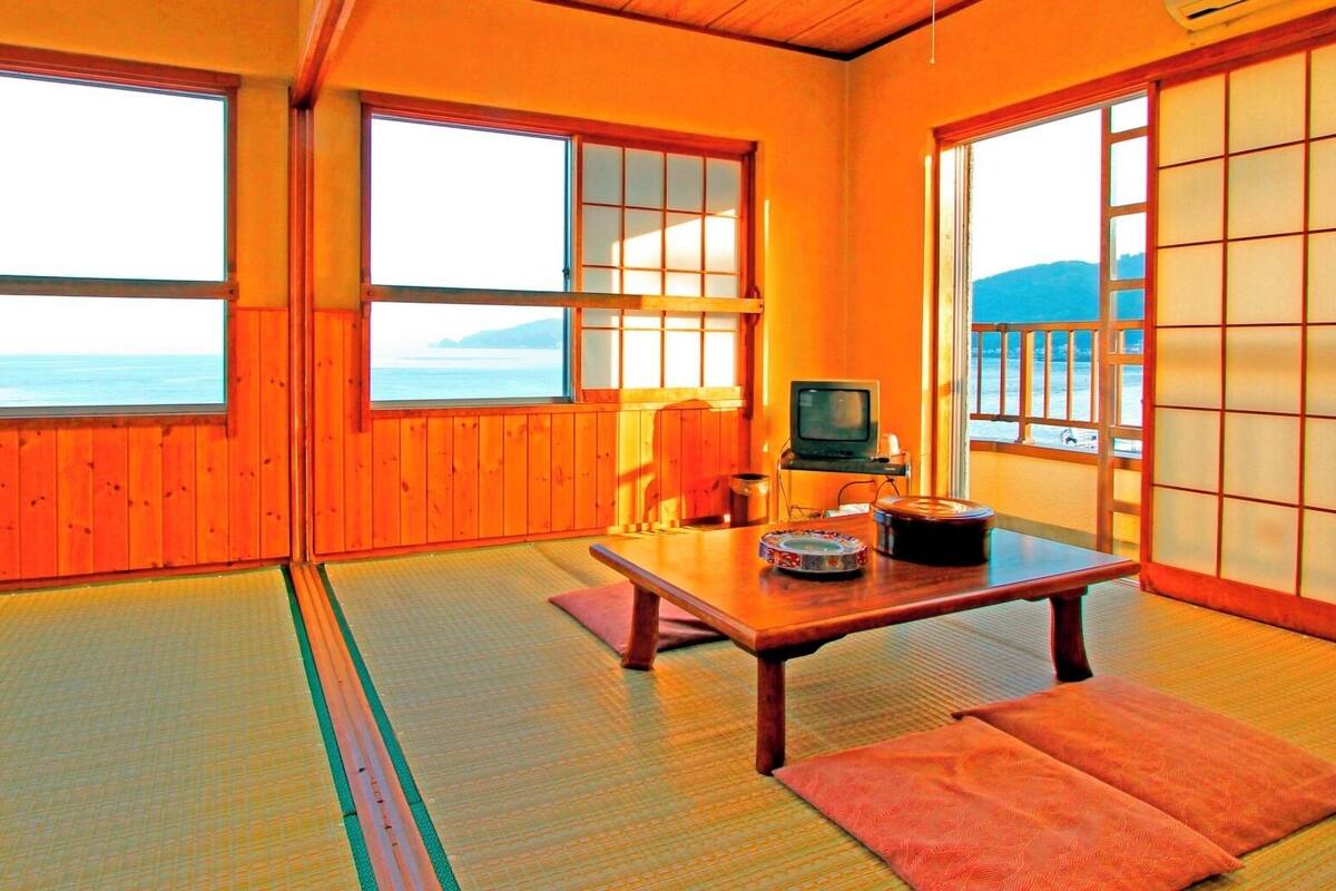 Ein traditioneller japanischer Raum mit Tatami-Böden, einem niedrigen Tisch und verschiebbaren Türen.