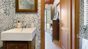 A bathroom with a sink, mirror, and patterned tiles. - Single Room in Green Setting with Wi-Fi and Workspace (Vicchio)
