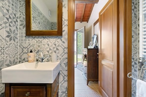 A bathroom with a sink, mirror, and patterned tiles. - Single Room in Green Setting with Wi-Fi and Workspace (Vicchio)