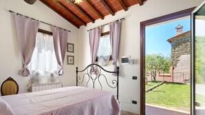 A bedroom with a bed, a window with curtains, a radiator, and a view of a garden. - Single Room in Green Setting with Wi-Fi and Workspace (Vicchio)