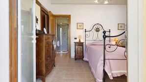 A bedroom with a bed, dresser, and a shower area. - Single Room in Green Setting with Wi-Fi and Workspace (Vicchio)