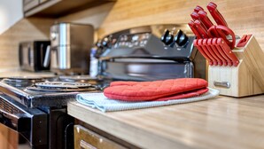A kitchen with a stove, oven, and a knife block with red handles. - Mins to Fort Benning - The Columbus Cottage Guesthouse (Columbus)