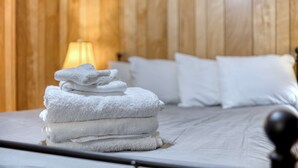 A neatly made bed with white linens and a stack of folded towels on the side. - Mins to Fort Benning - The Columbus Cottage Guesthouse (Columbus)