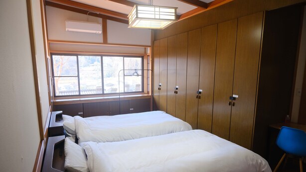 A bedroom with two beds, a window, a wardrobe, and a blue chair. - Daigo-sauna (Daigo)